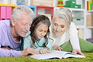 Grandparents reading book with little granddaughter photo