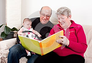 Grandparents reading book to baby girl