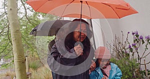 Grandparents running in the rain with their grandchildren into their home. Old man and woman on a rainy day going into a