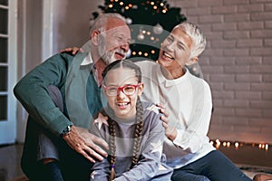 Grandparents and their granddaughter gathered around a Christmas tree, smiling