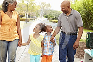 Grandparents Walking Grandchildren In Park