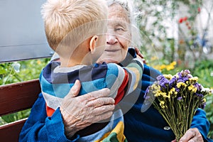 Grandson boy giving a flower to grandma. Grandson and grandmother spending time together. Granny with grandsons enjoying