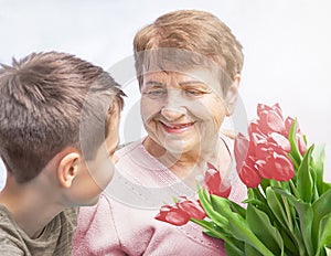 Grandson congratulates grandma (over the age of 50) on holiday. Grandmother has a bunch of flowers. photo