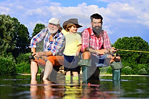 Grandson with father and grandfather fishing by lake. Father, son and grandfather on fishing trip. Family bonding