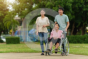 grandson and granddaughter pushing senior woman in wheelchair at park