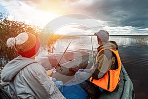 Grandson and grandfather together fish from a boat on the lake. The concept of family, summer vacation, generation. Copy space