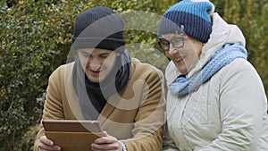 Grandson and grandma talks with relatives on video call at the tablet outdoors