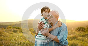 Grandson and granfather spending time together on summer meadow