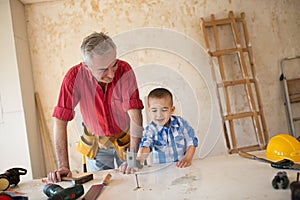 Grandson is helping grandfather in a carpenter`s workshop