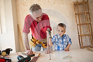 Grandson is helping grandfather in a carpenter`s workshop