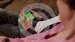 A grandson with his grandmother holding a phone with a green screen.