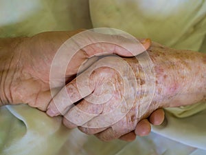 Grandson holding his grandmother`s hand in the hospital