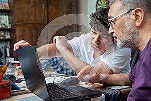 Grandson is Pointing to his Grandfather at Laptop Monitor