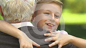 Grandson running to grandfather and tightly hugging him, relationship in family