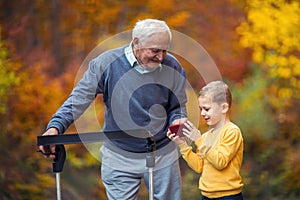 Grandson showing something on phone in the park disabled senior grandfather