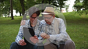 The grandson shows his granfather interesting information on the tablet