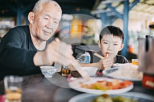 Granfather ehjoy dinner with her grandson in restaurant