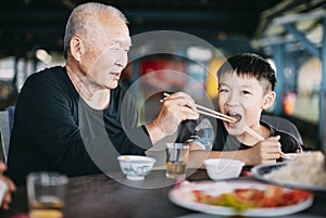 Granfather feeding her grandson in restauran