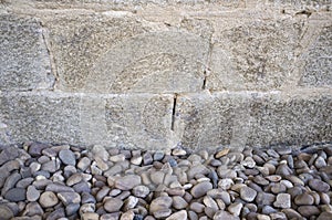 Granite ashlars wall with river pebble stones as ground photo
