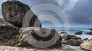 Granite boulders are piled on the ocean shore and scattered in the water.