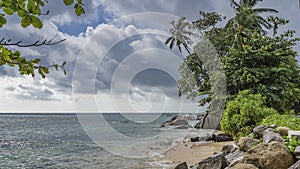 Granite boulders are scattered on the beach of a tropical island.