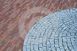 Granite circle arch of cubes around brick paving combined to create a beautiful contrast of gray and red colors of the paving town