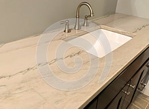 Granite countertop with white sink and chrome faucet on dark wood cabinets, tile floor inside bathroom