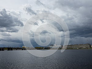 Granite embankment of the river with storm clouds over the water