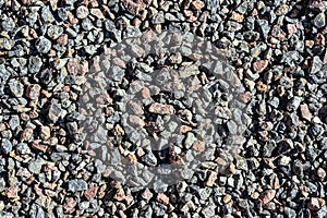 Granite gravel. Brown and gray crushed rocks for construction on the ground. Gravel macadam road texture or background.