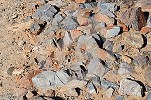 Granite large rocks and pebbles, some covered in iron oxide, strewn across the hiking trail of the Horseshoe Loop in Arizona