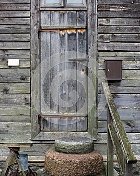 Granite millstones lie in front of the door of a rustic barn