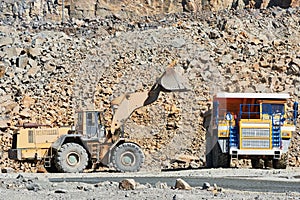 Granite mining. Wheel loader loading ore into dump truck at opencast