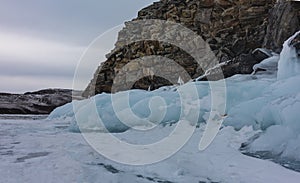 A granite rock devoid of vegetation rises on a frozen lake