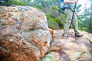 Granite rock in foreground with hiker in background in Acadia National Park, Maine