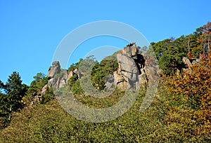 Granite rocks heavily weathered and smoothed by frost and wind. they form rock towers and outcrops in a pine forest with a lack of