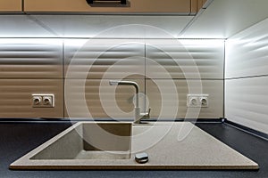 Granite sink and water faucet in new modern kitchen interior