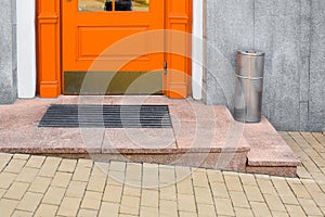 Granite threshold with foot mat near orange wooden front door.