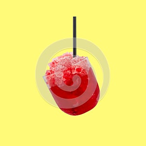Granizado or Shaved ice with Fruit juice. Red Slush drink isolated on yellow background. Summer refreshment drink