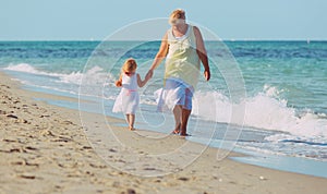 granmother with little granddaughter walk on beach