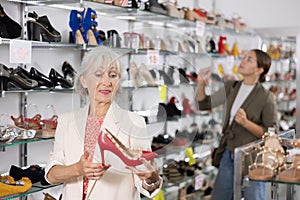 Granny choosing shoes while standing in salesroom of shoeshop
