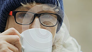 Granny drinks coffee and looks in camera