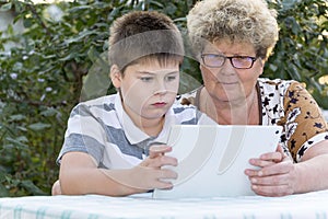 Granny with grandson watching tablet in nature