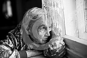 Granny older woman sadly looking out the window.