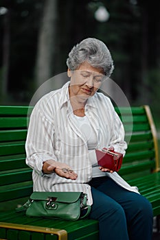 Granny shows a trifle in her wallet in summer park