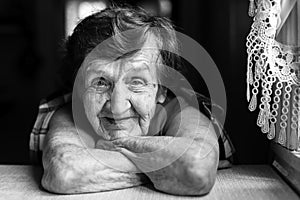 Granny is sitting near the window in the kitchen.