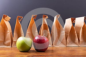 Granny smith apple and apple by paper lunch bags arranged on table against black background