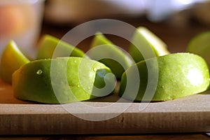 Granny smith pieces on chopping block, cutting board