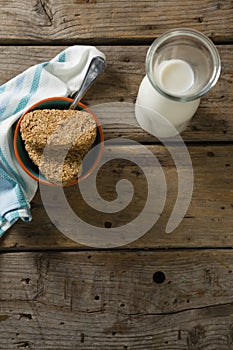 Granola bar and milk with napkin on wooden table