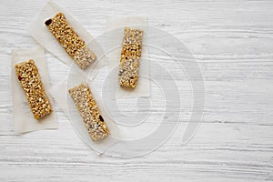 Granola bars on baking sheet over white wooden background, overhead view.