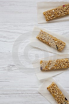Granola bars on baking sheet over white wooden background, top view. Overhead, from above.
